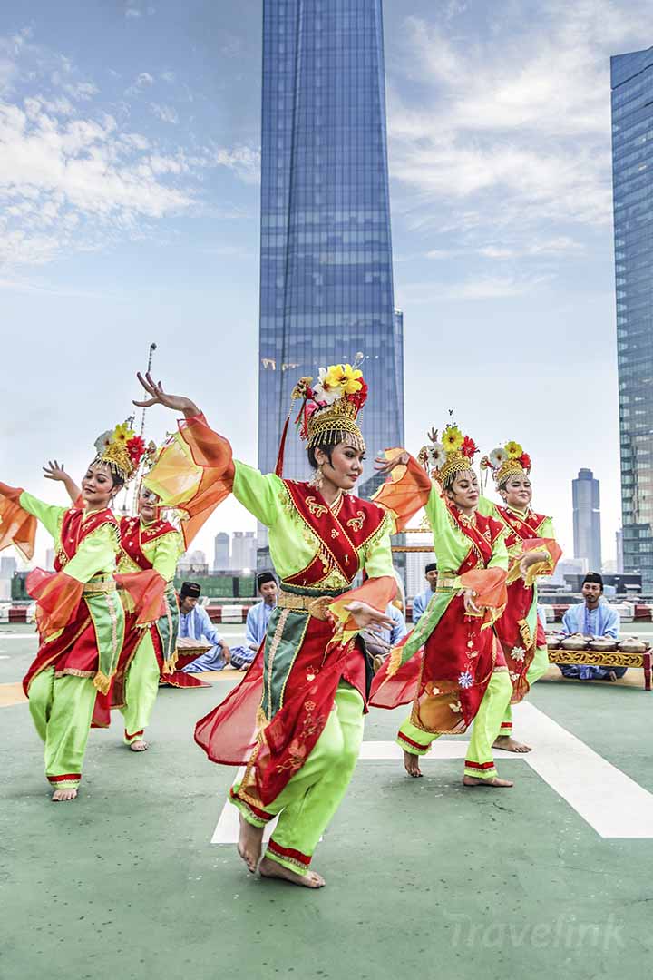 Penari tradisional Betawi membawakan tarian dengan latar belakang gedung pencakar langit Jakarta